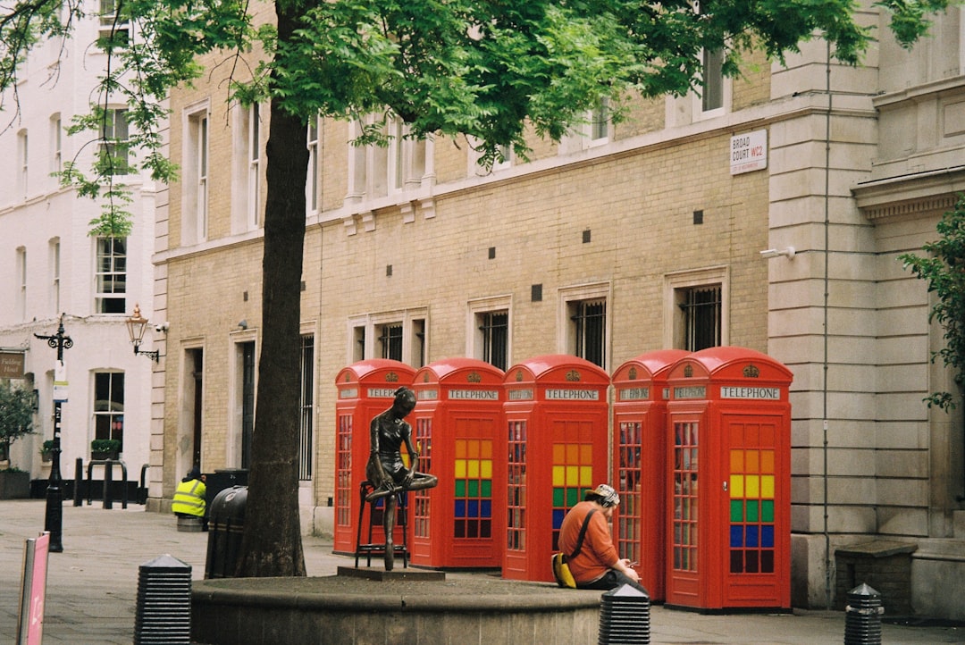 a group of red phone booths sitting next to a tree — Photo by Chun Chen on Unsplash