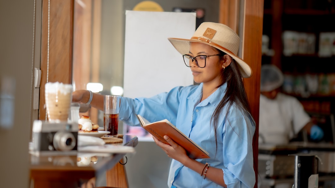 A woman wearing a hat and reading a book — Photo by Shane Ryan Herilalaina on Unsplash