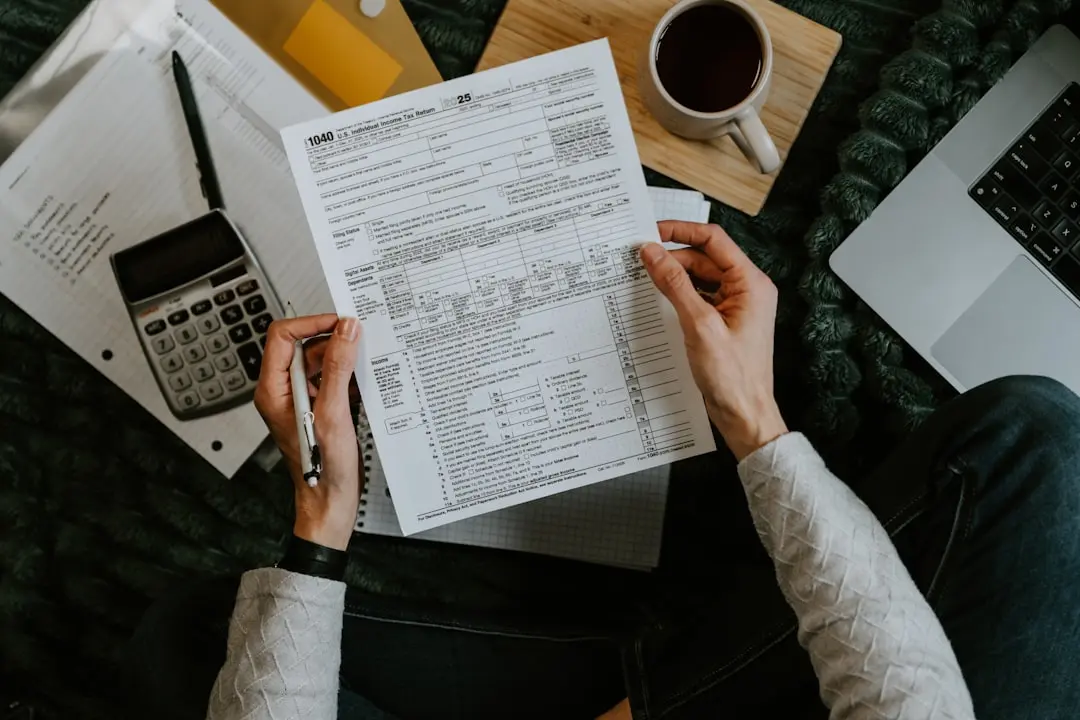 Hands holding tax forms with calculator and laptop. — Photo by Kelly Sikkema on Unsplash