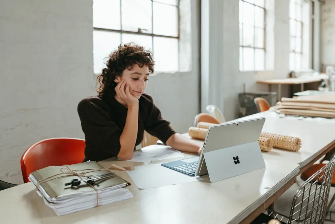 a woman sitting at a table with a laptop — Photo by Surface on Unsplash