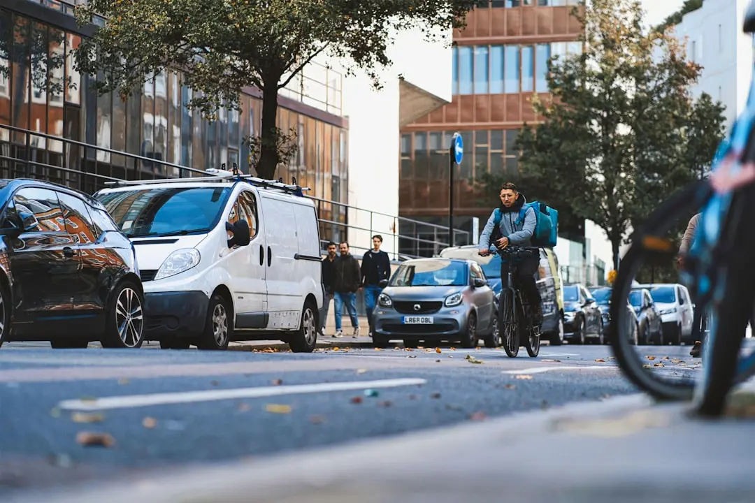 a man riding a bike down a street next to parked cars — Photo by Anthony Fomin on Unsplash