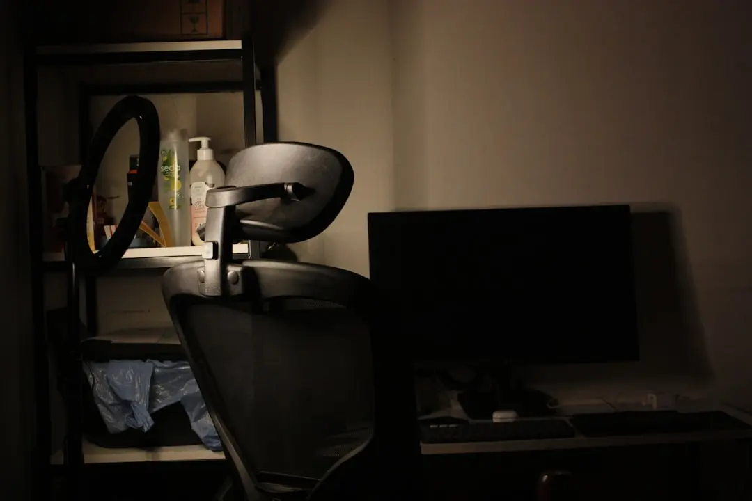 Desk with chair and computer in dim lighting — Photo by Clevenider Petit on Unsplash