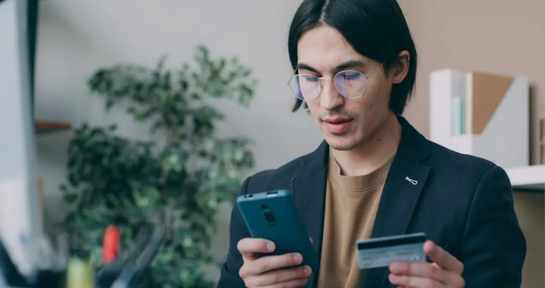 A man holding a smart phone and a credit card — Photo by Vitaly Gariev on Unsplash