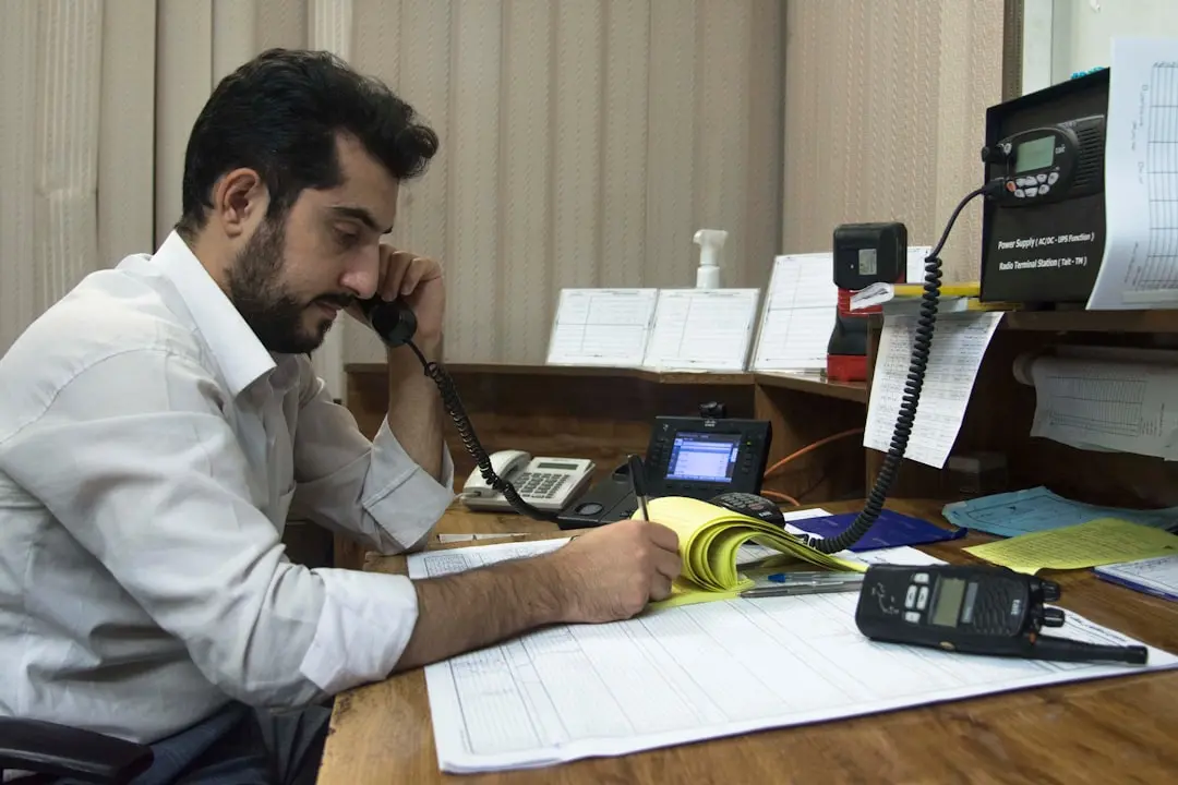 a man sitting at a desk talking on a phone — Photo by Javad Esmaeili on Unsplash