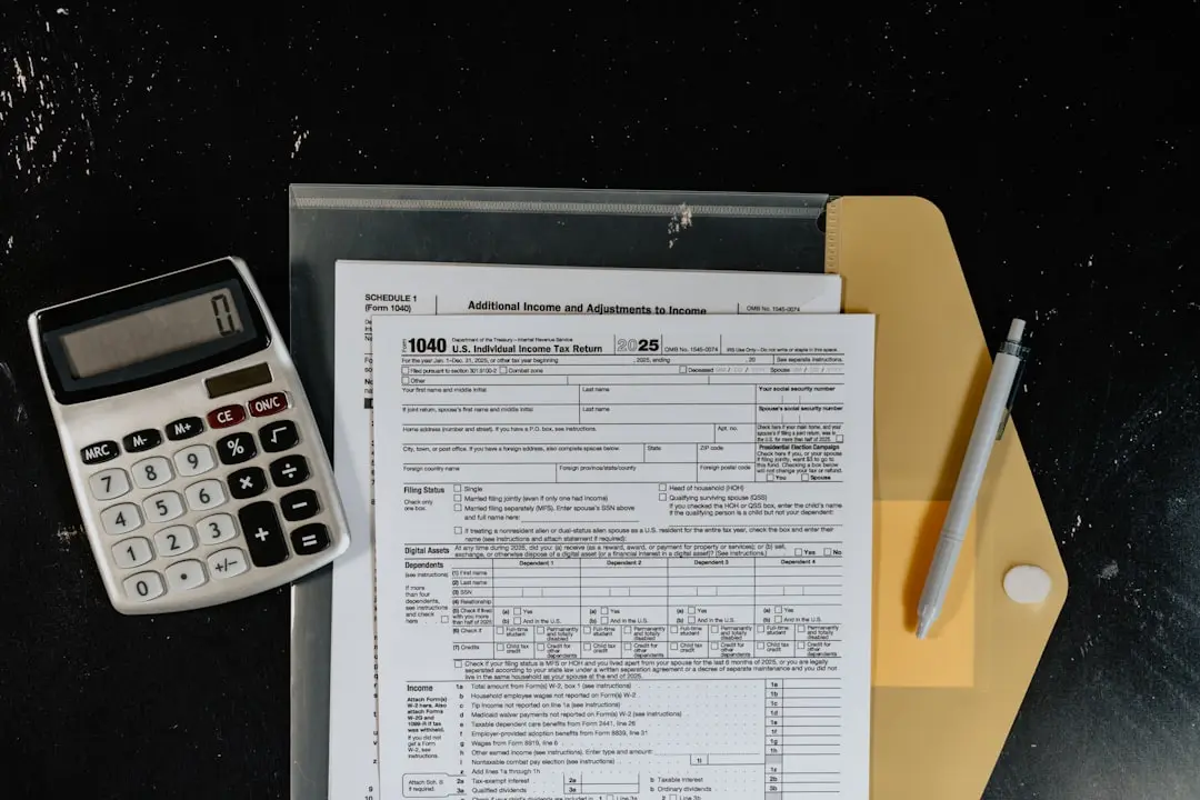 Calculator and tax forms on a dark surface. — Photo by Kelly Sikkema on Unsplash