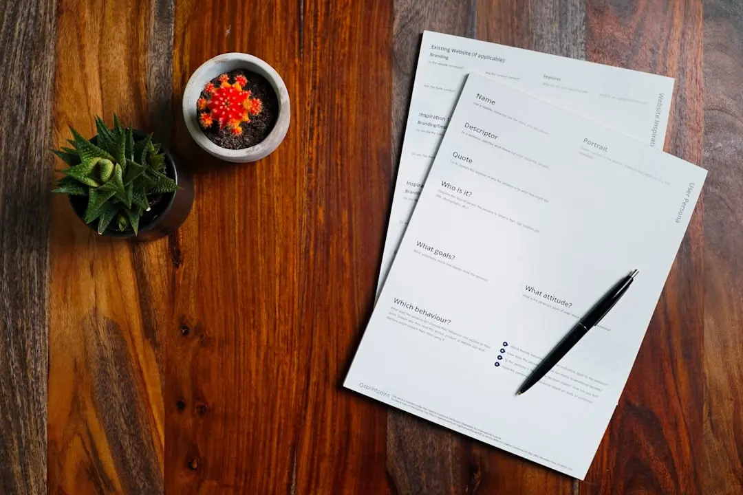 a wooden table topped with papers and a pen — Photo by 2H Media on Unsplash