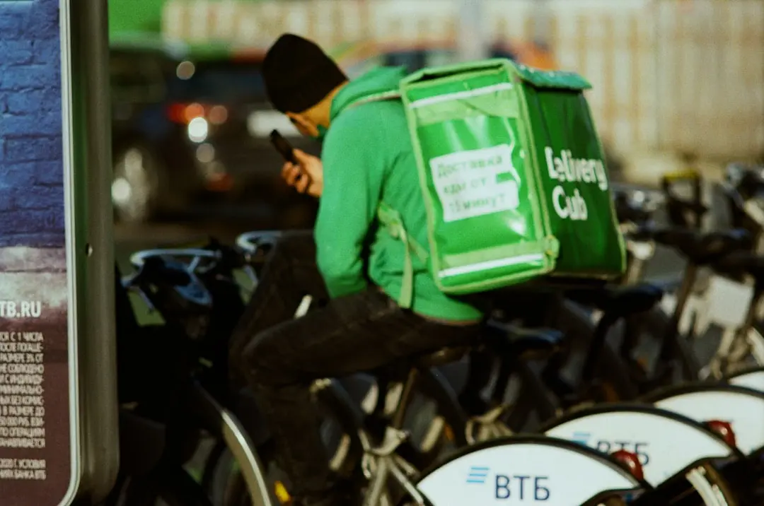 A man sitting on a bike with a bag on his back — Photo by Maxim Makarov on Unsplash