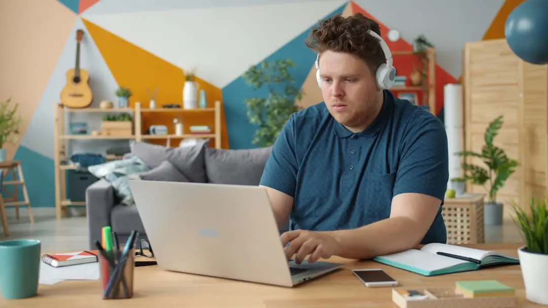 Man wearing headphones works on laptop at desk. — Photo by Vitaly Gariev on Unsplash