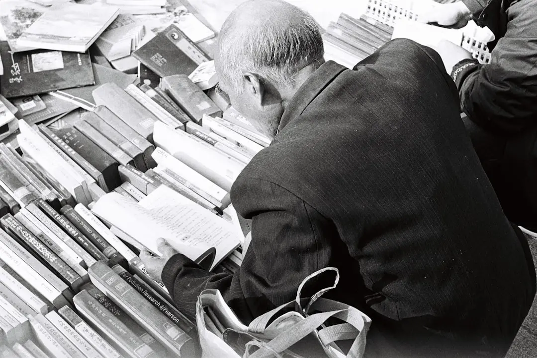 a man sitting on a bench next to a pile of books — Photo by Sherwin Ker on Unsplash