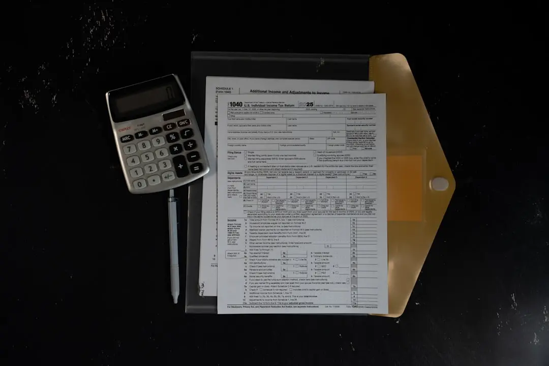 Calculator and papers in a folder on a dark surface — Photo by Kelly Sikkema on Unsplash