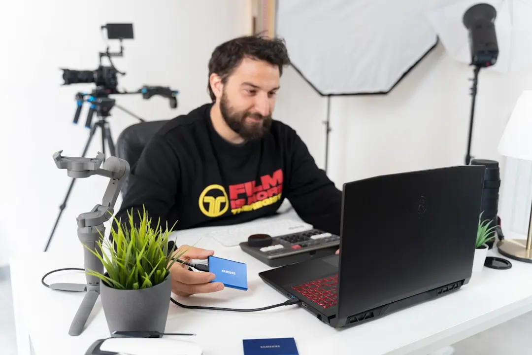 a man sitting at a desk with a laptop and a camera — Photo by TheRegisti on Unsplash