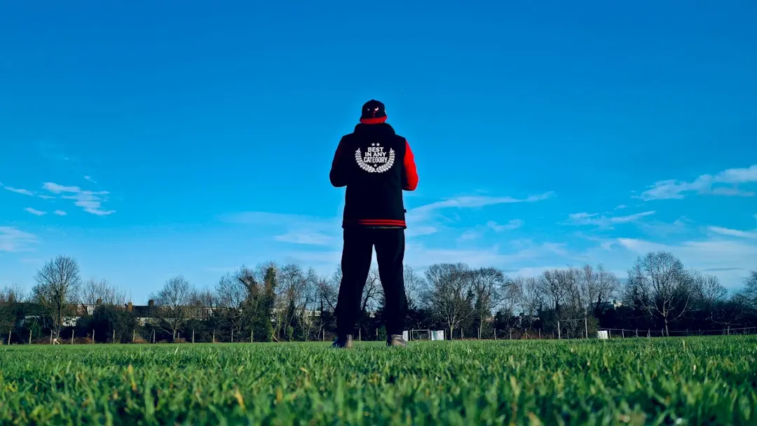 man in black hoodie standing on green grass field under blue sky during daytime — Photo by Jay Mullings on Unsplash