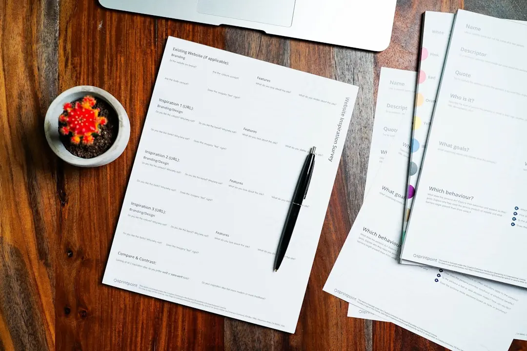 a wooden table topped with papers and a pen — Photo by 2H Media on Unsplash