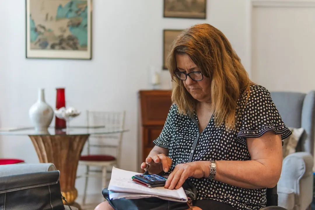 Woman using calculator with papers on table. — Photo by Centre for Ageing Better on Unsplash