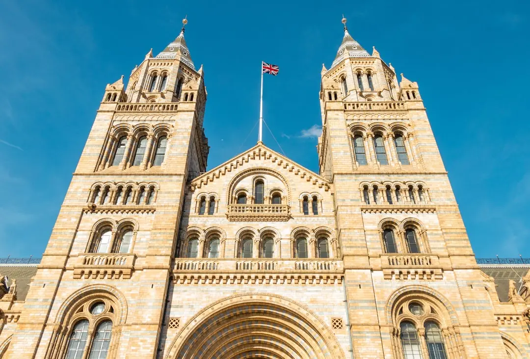 a tall building with a flag on top with Natural History Museum in the background — Photo by Luis Wittenberg on Unsplash