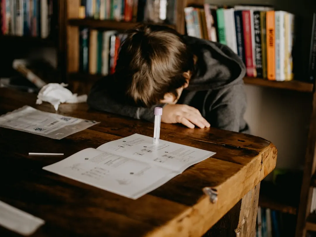 boy in gray hoodie reading book on brown wooden table — Photo by Annie Spratt on Unsplash