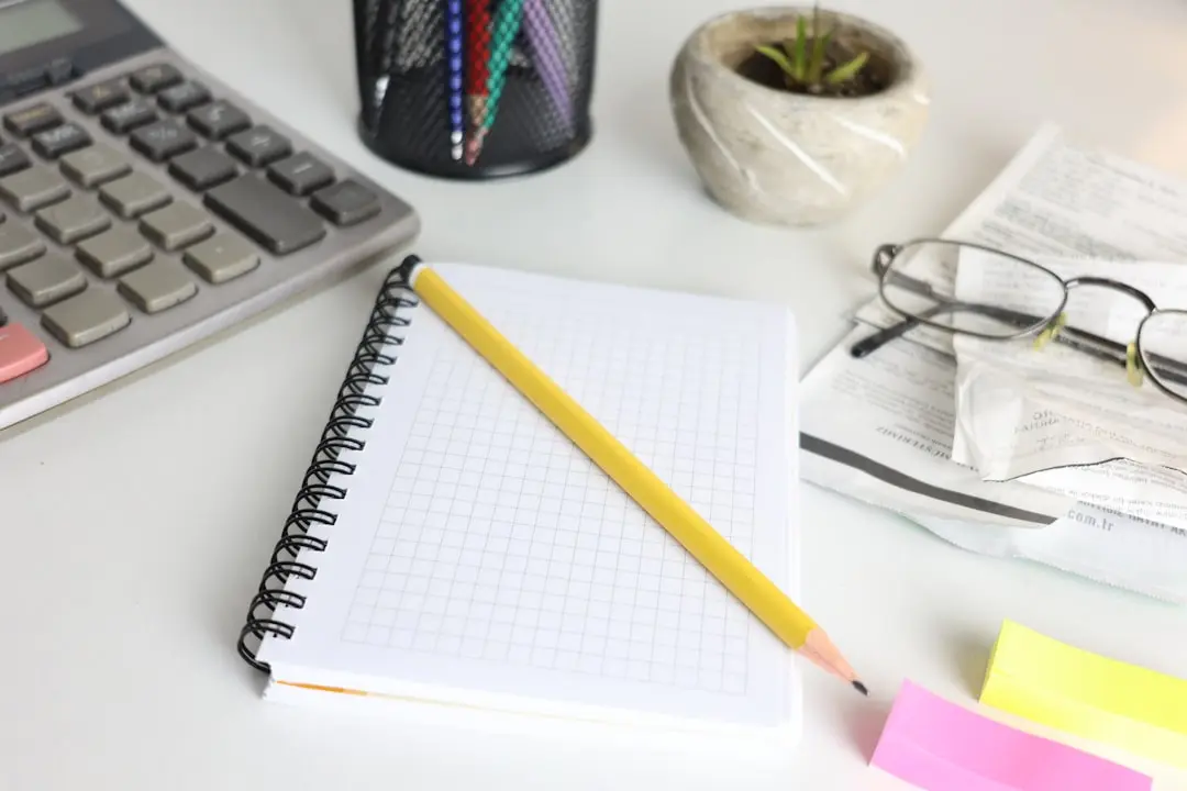 Desk with calculator, notebook, pencil, and glasses. — Photo by Cht Gsml on Unsplash